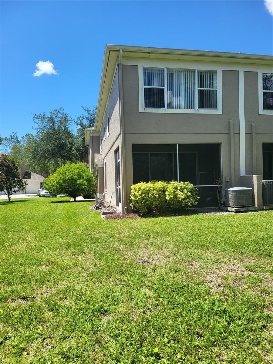 Exterior view of back of unit shows large Primary Suite window above the patio