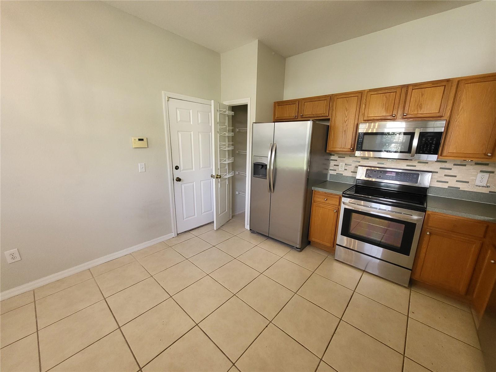 Kitchen boasts wood cabinets, stainless steel appliances, a closet pantry and room for a table & chairs.  Closed door leads to garage.