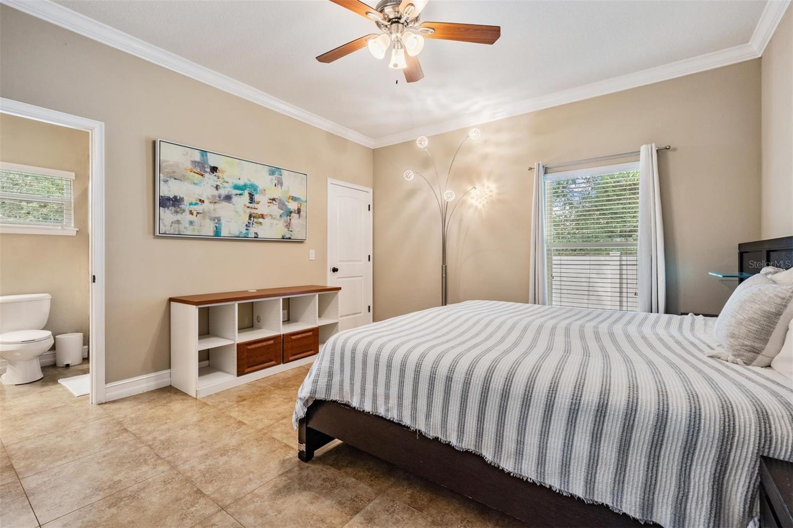 primary bedroom with ensuite bathroom, walk in closet with custom built-ins, and wall-to-wall storage built in