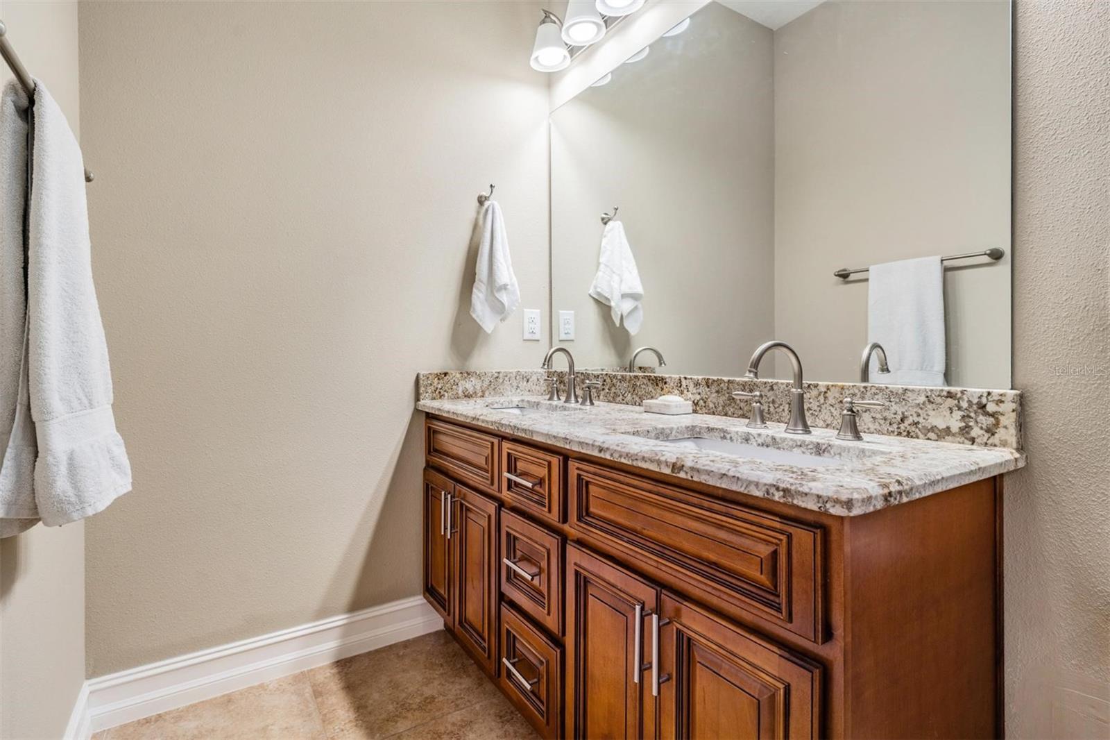 primary bathroom featuring granite countertops & dual vanities