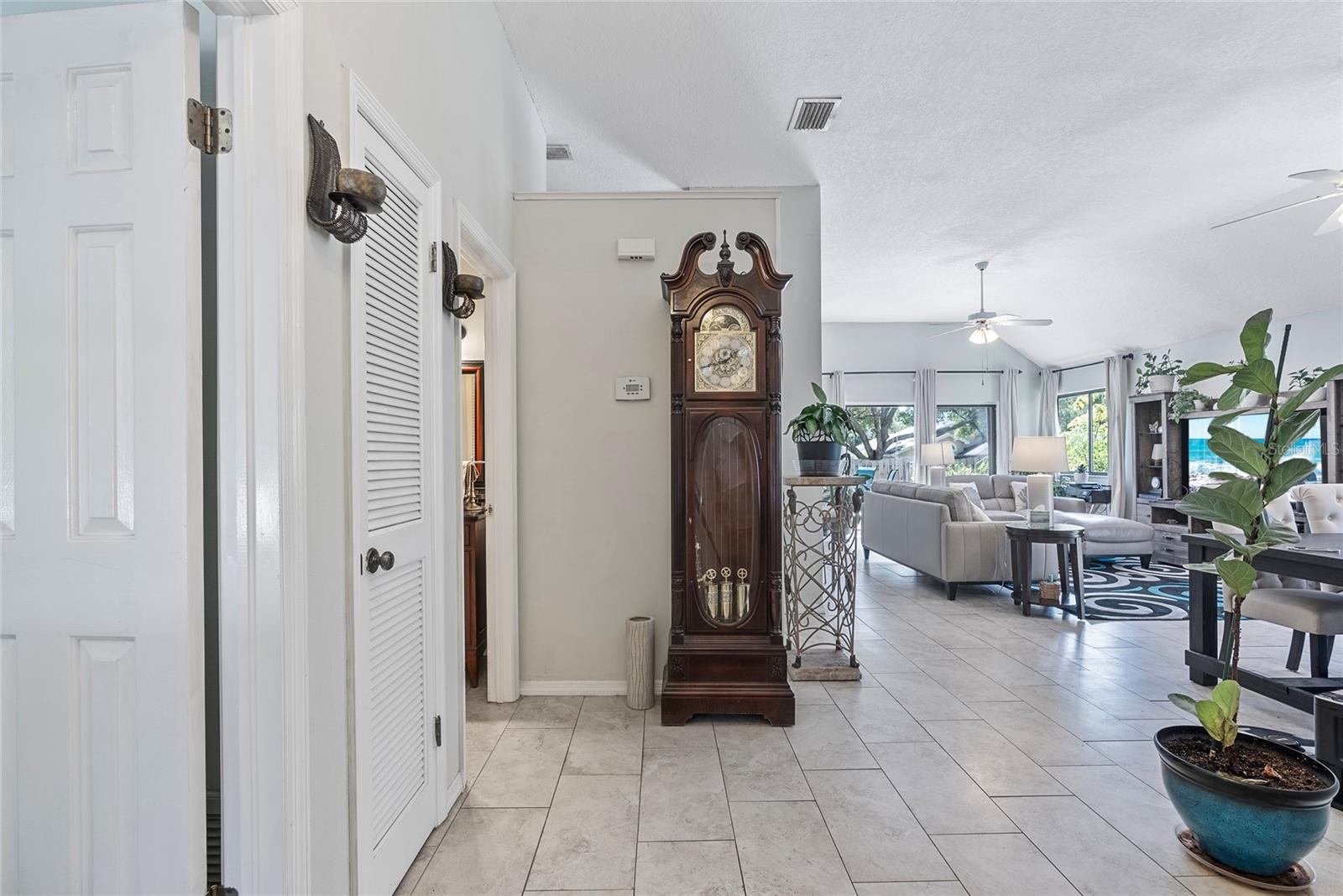 Entry foyer with living room & dining room in the background.  Entrance to the guest bedroom is the door to the left of the grandfather clock.  Entrance to the guest bedroom is the door on the left of this photo (in front of the louvered door)