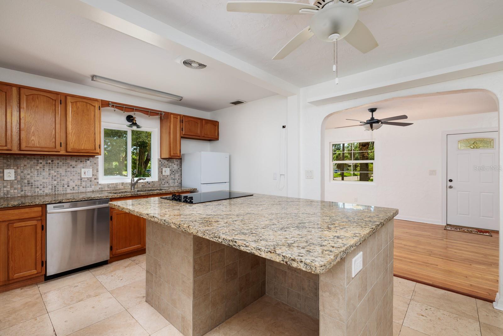 Breakfast bar, cooktop on granite island that has an extra electrical outlet.