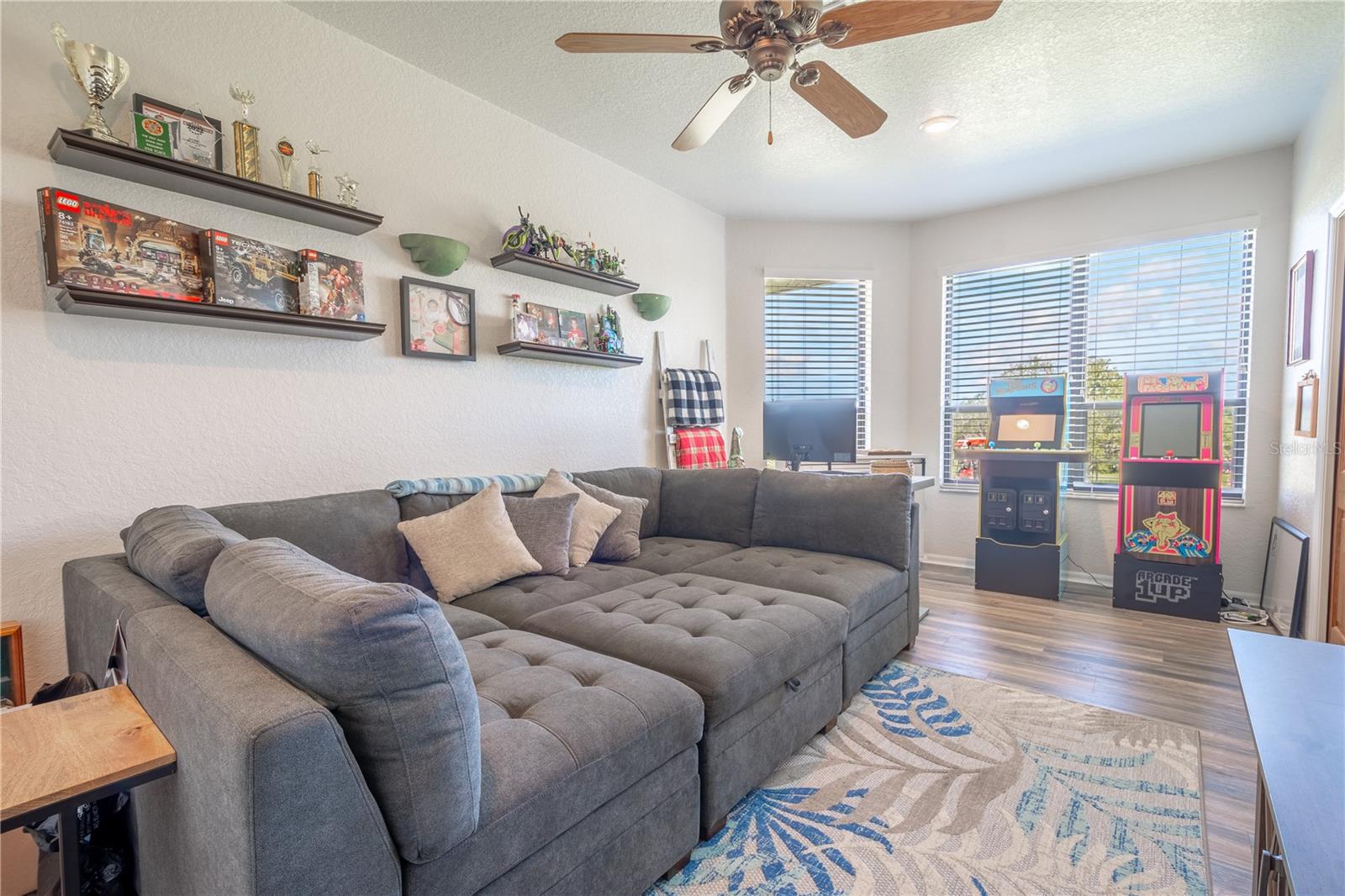 Bedroom 3 is currently used as a den and game room. It has wood laminate flooring, a ceiling fan, and a built-in closet.