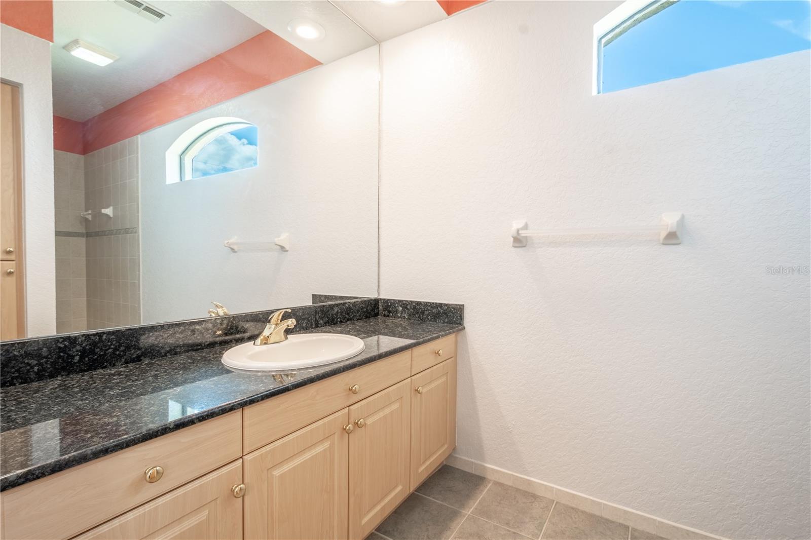 Bathroom 2 (an ensuite) features a mirrored vanity with storage and granite counter top, and ceramic tile floor.