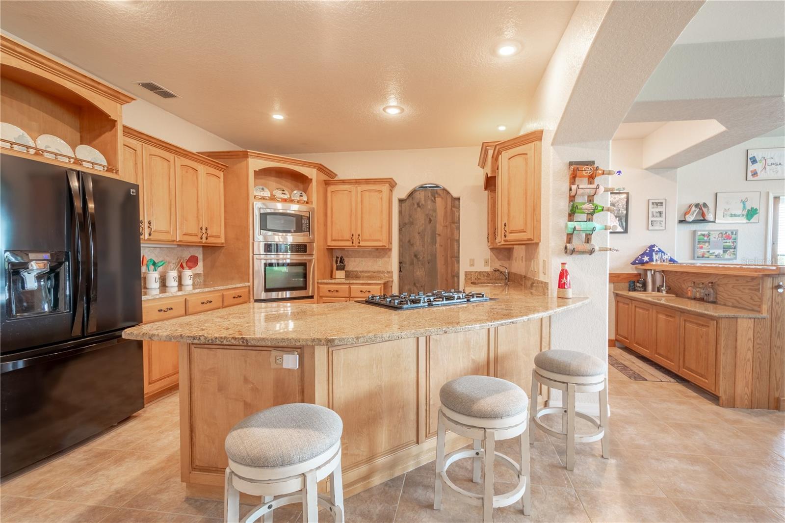 The kitchen features solid wood cabinets, a breakfast bar, with granite countertops, a gas cooktop, a built-in convection oven, microwave and French door refrigerator with water dispenser and ice maker.