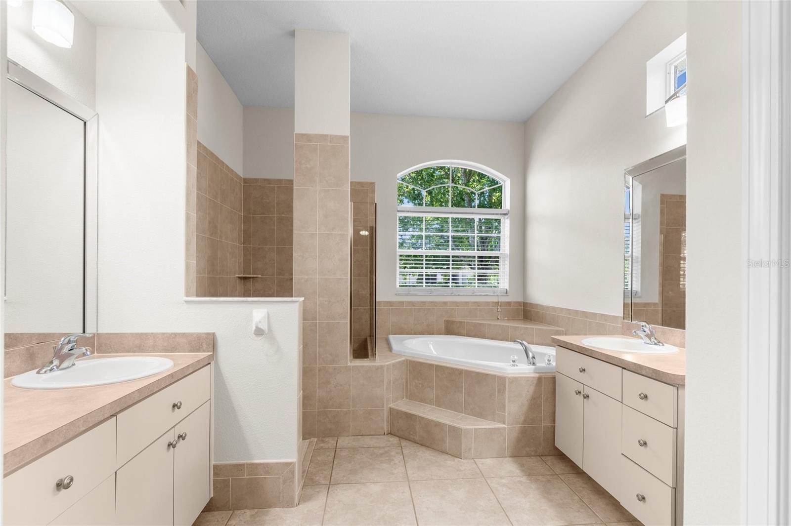 Master bathroom with dual vanities and sinks, soaking tub, walk-in shower