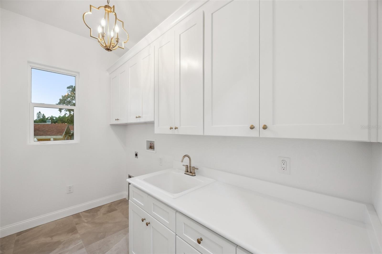 Laundry room equipped with a sink, ample countertop space, and cabinetry.