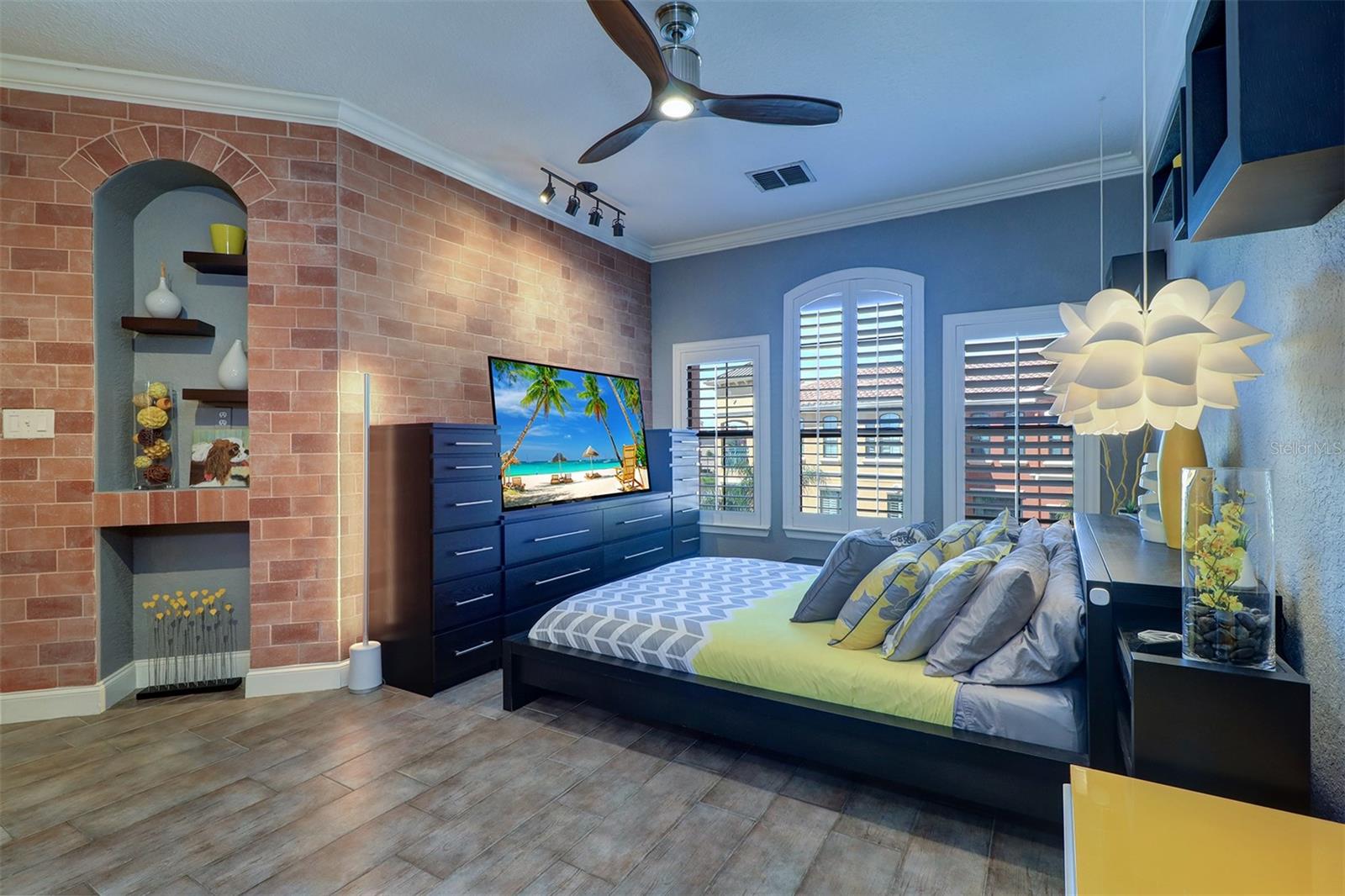 Primary bedroom with decorative niche, feature wall, wood looking ceramic flooring and wall of windows