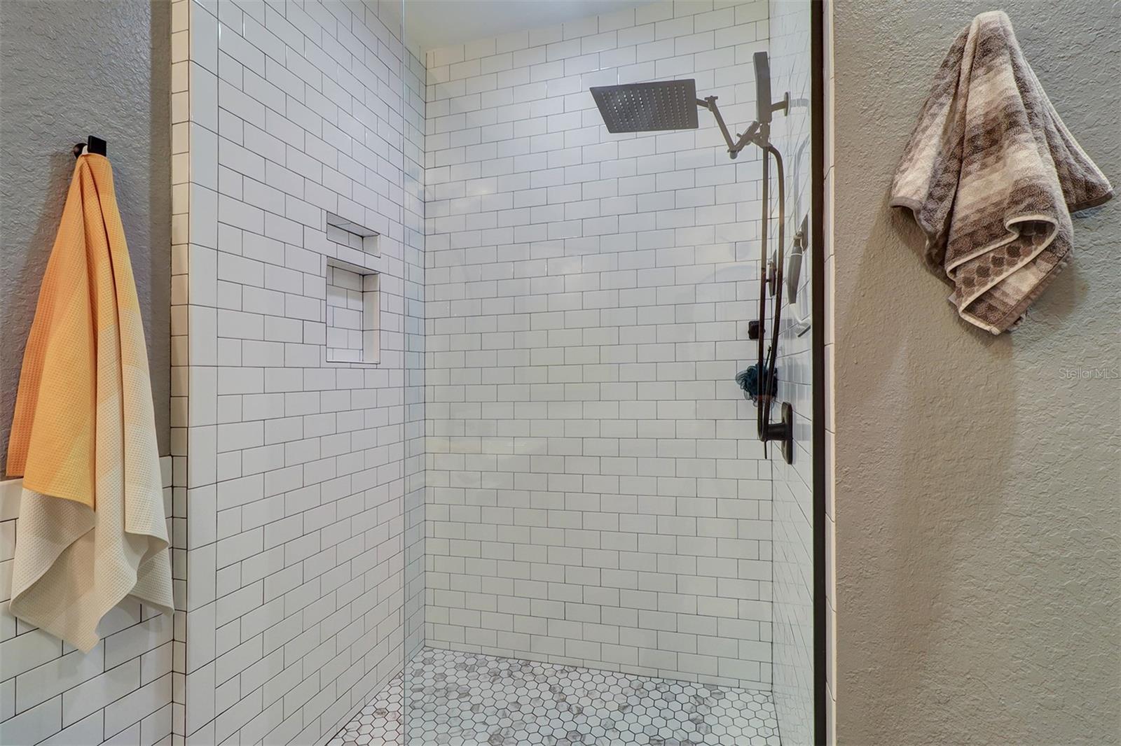 White subway tile shower with hexagon tile flooring