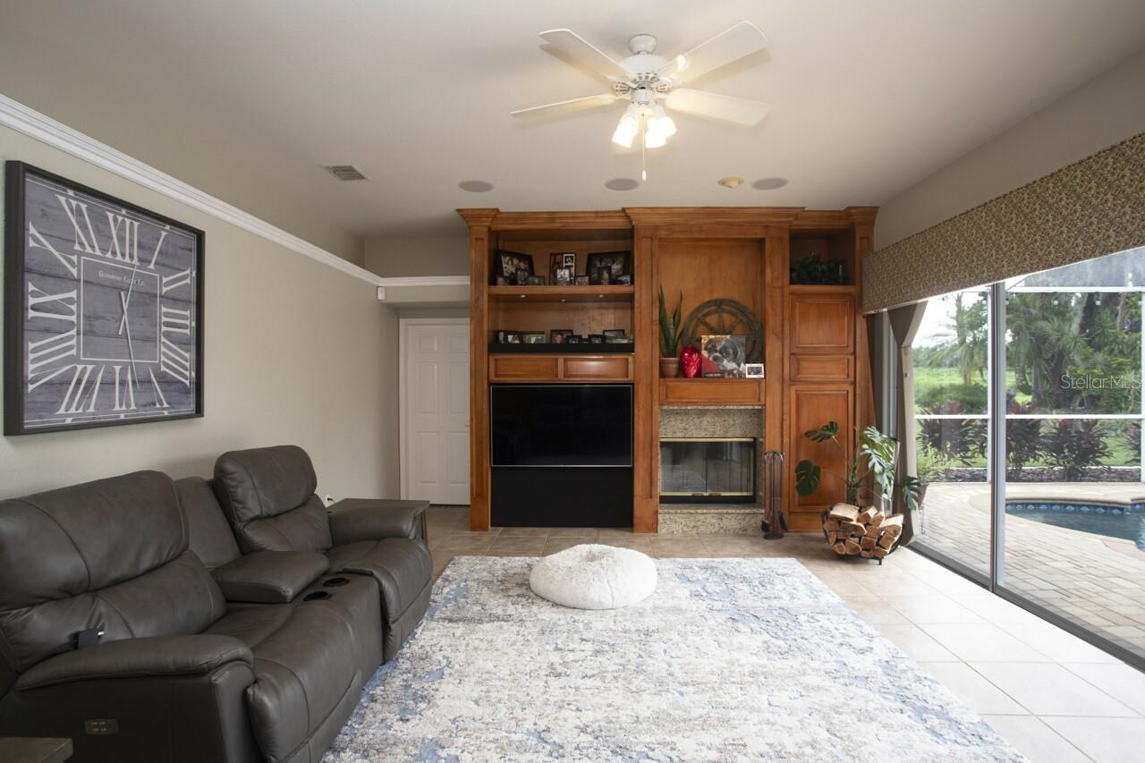 Open and Airy with natural light filtering through the Family Room with wood fireplace & great pool view