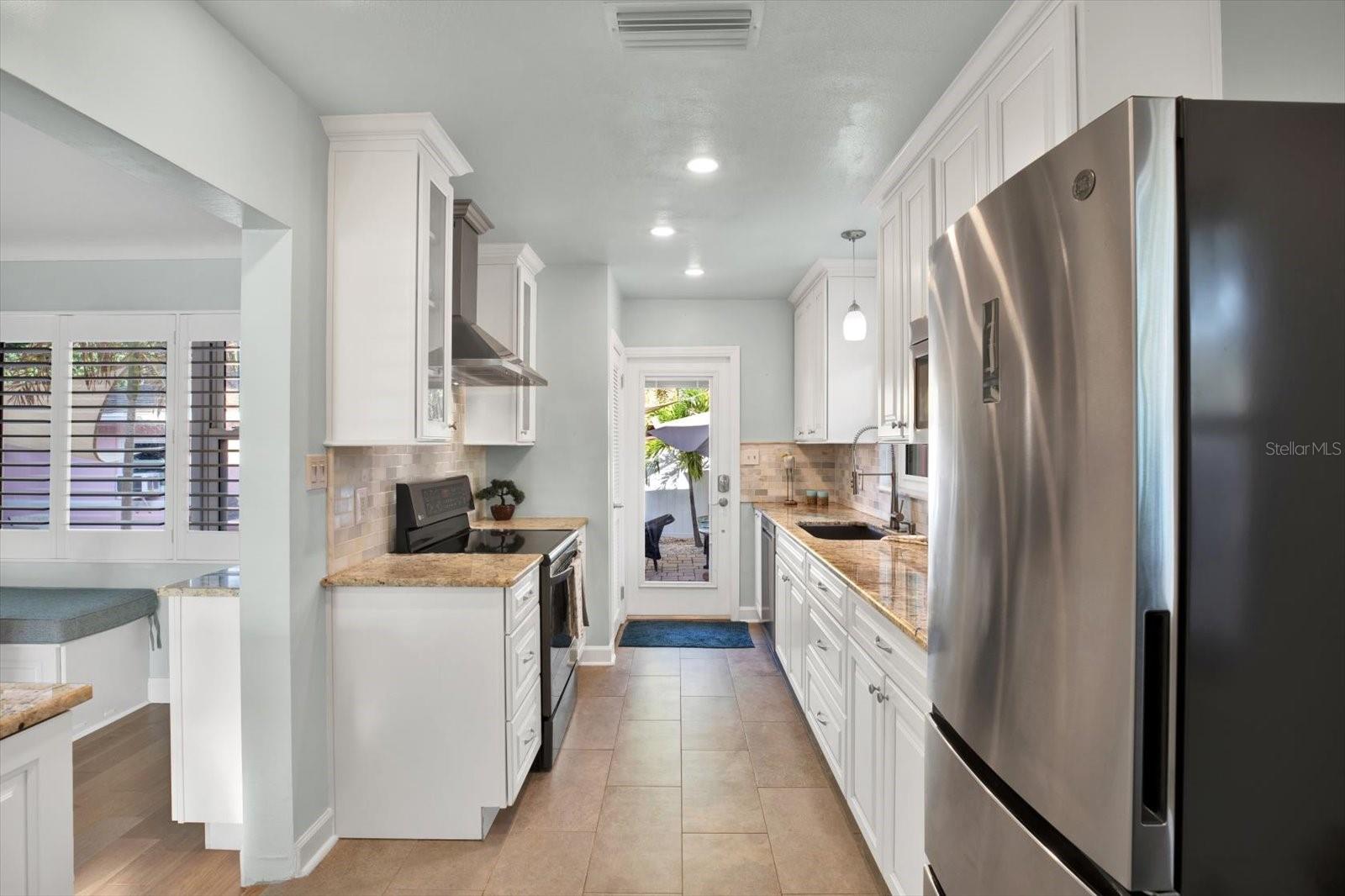 Door to the backyard patio is just through the kitchen! Perfect for popping in from outside to grab more watermelon and iced tea. . .