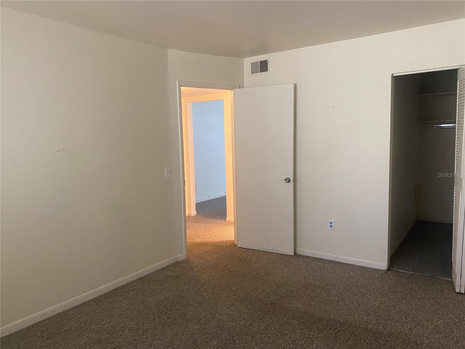 Bedroom. Opening on right is the walk-in closet and opening on the left is the entrance door ( which leads back to the hall) Behind you are a set of windows which look out into the Florida room