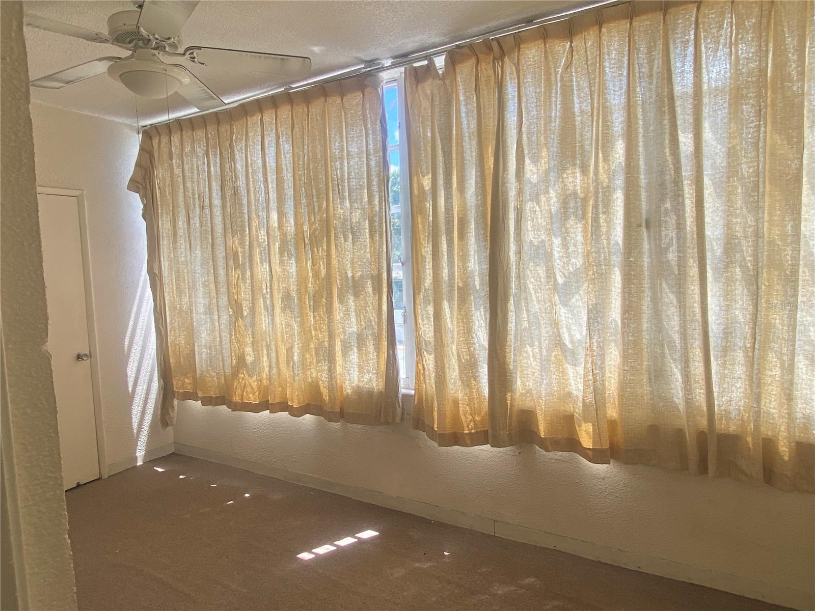 In the doorway of the kitchen, view into the Florida room. Storage closet on far left. Windows look out over the assigned parking spots on the south side of the building