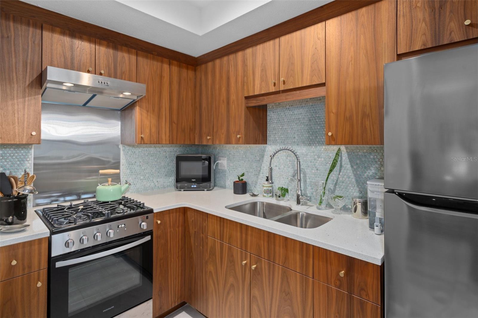 The kitchen features modern wood tone cabinetry and a stunning decorative tile backsplash.