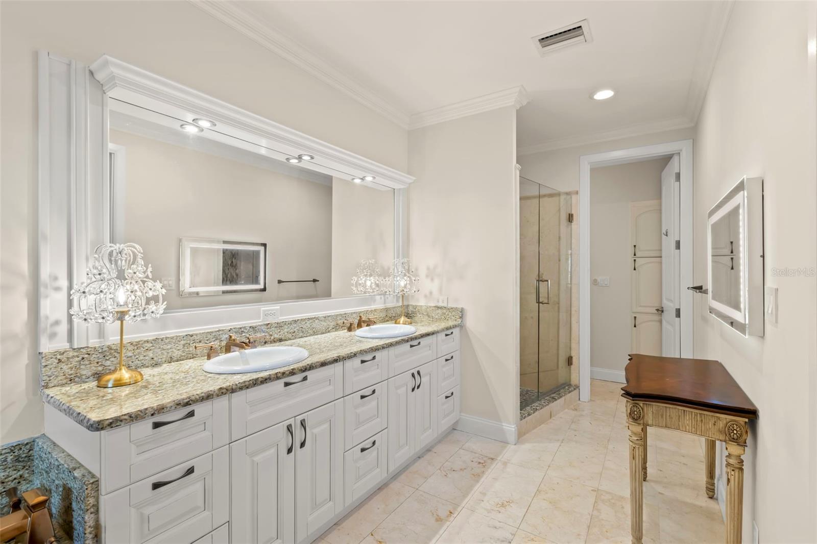 Spacious and elegant primary bathroom featuring dual sinks, a large vanity with plenty of storage, and a glass-enclosed shower for a touch of luxury.