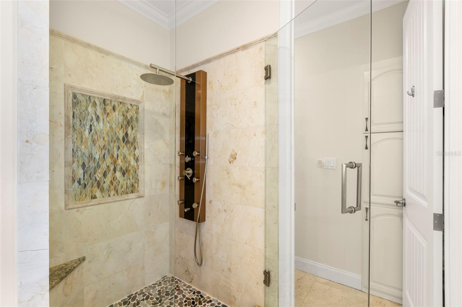 Enjoy a spa-like experience in this luxurious shower, featuring a rainfall showerhead, multi-function body jets, and elegant tile accents.