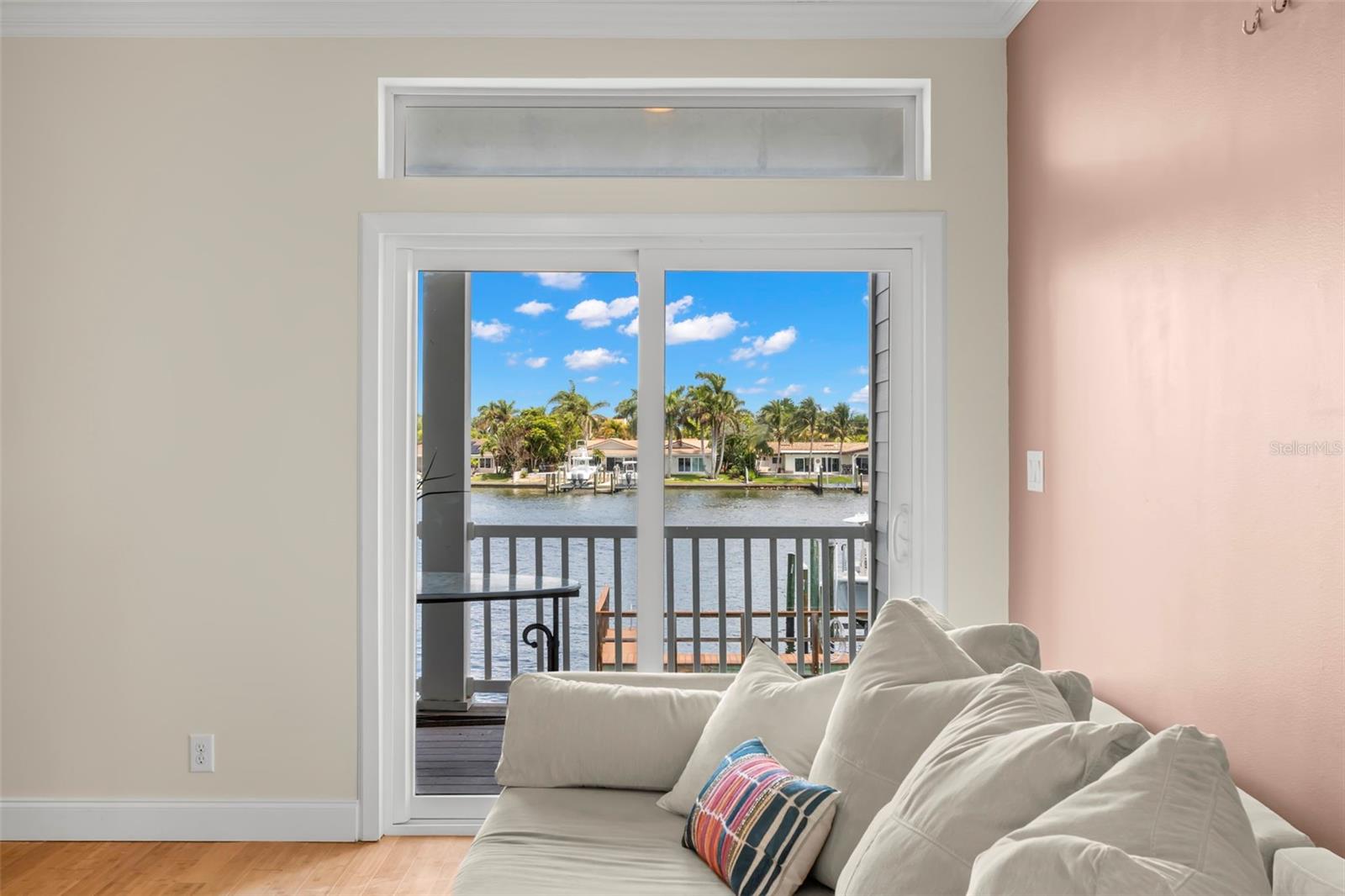 Your daily view: tranquil waters and swaying palms. This inviting living space flows seamlessly onto the balcony, offering the perfect spot to unwind and take in the coastal beauty.