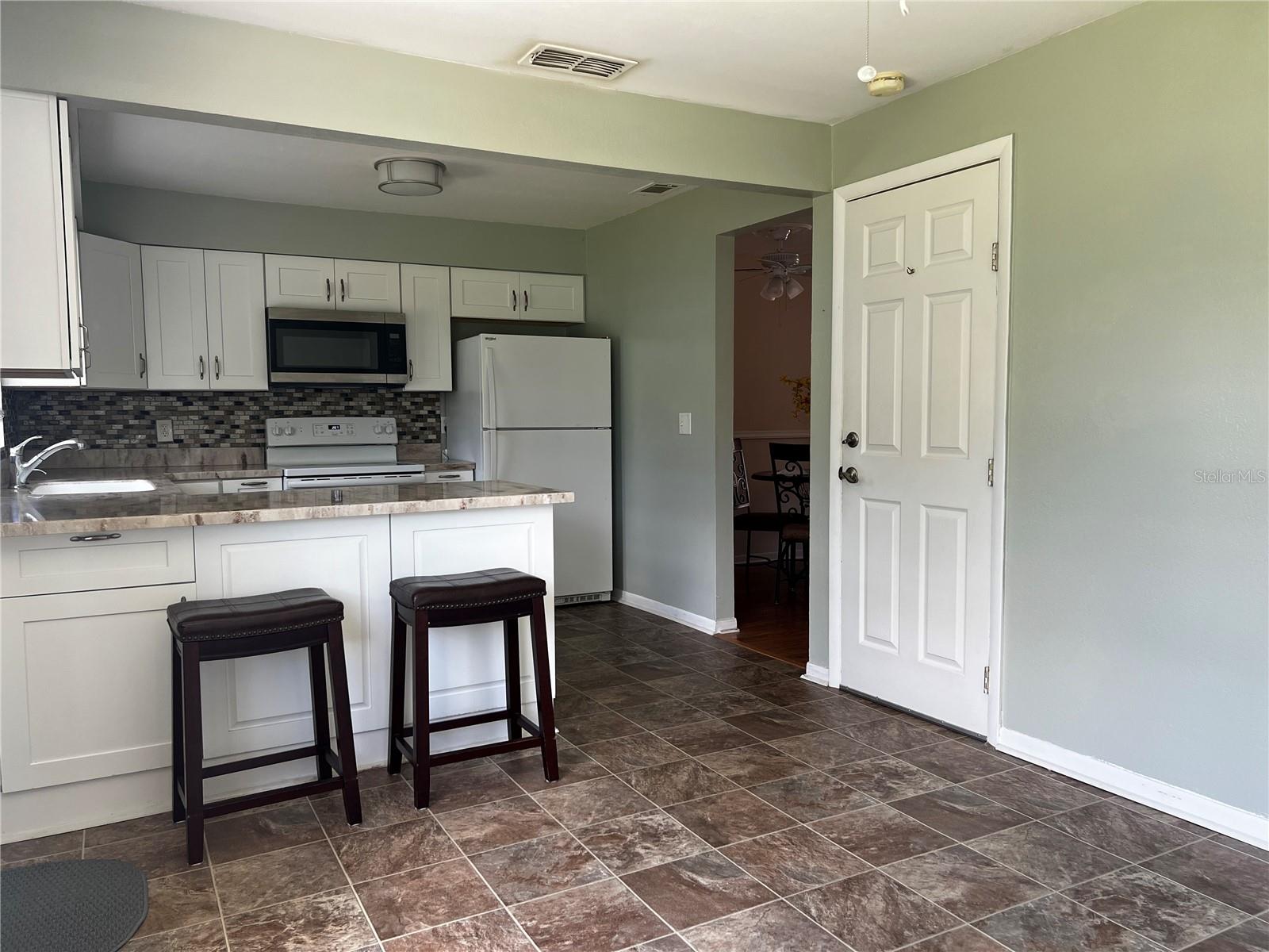 Kitchen and Den with Garage entrance through door on the right side of the photo.