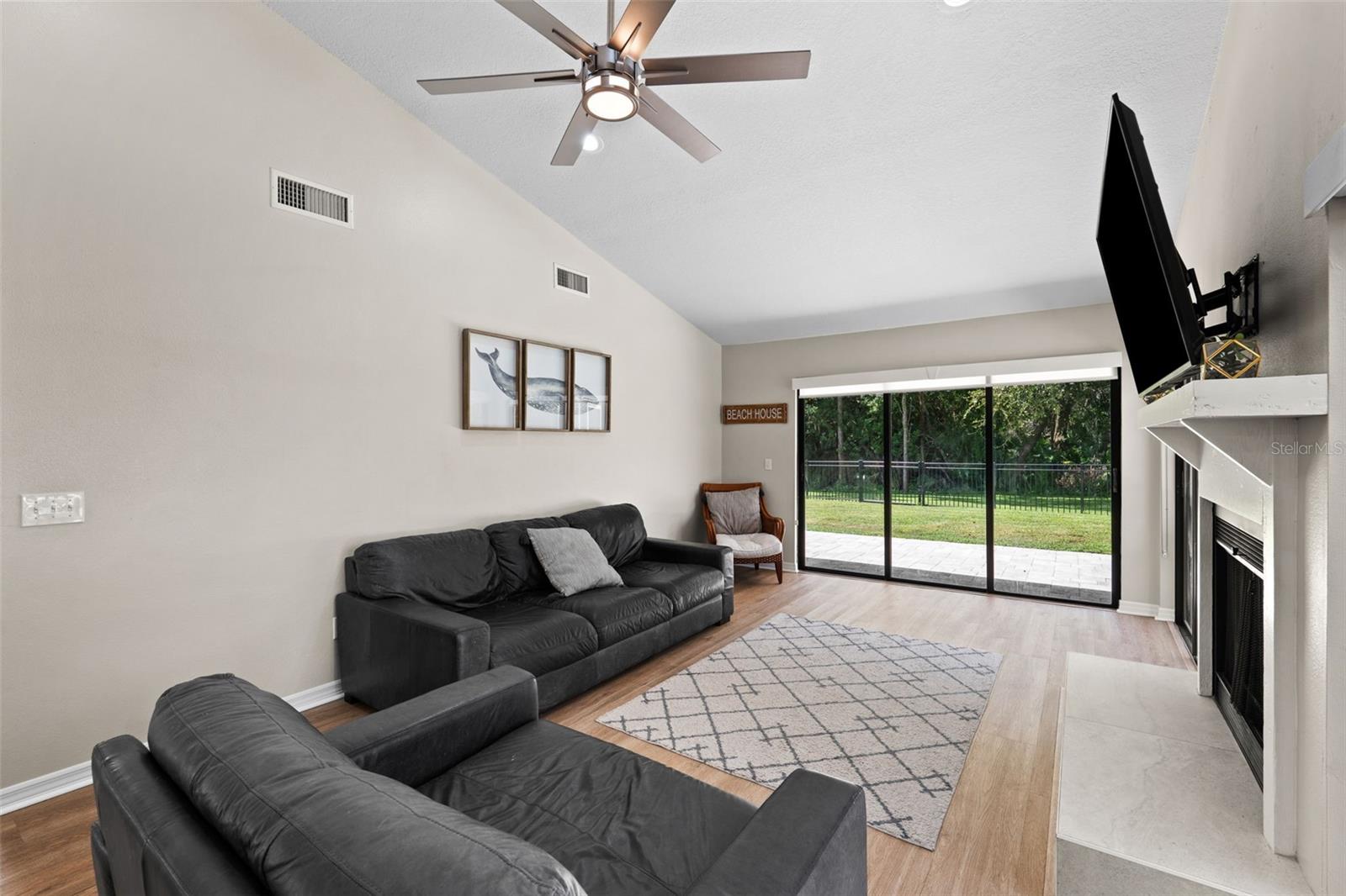 Living room with sliders to fenced backyard and paver lanai