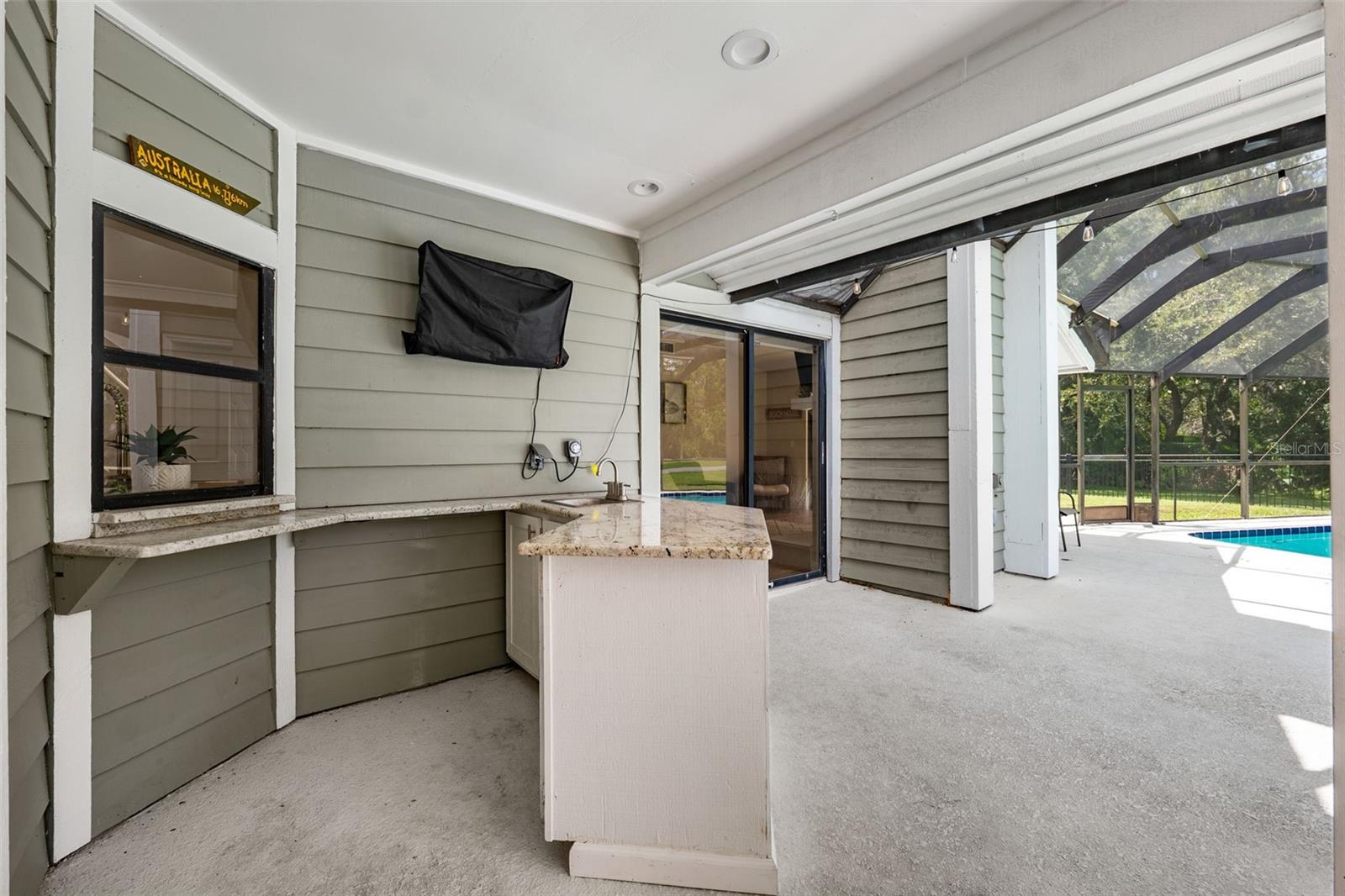 Outdoor kitchen/wet bar and TV in covered pool area