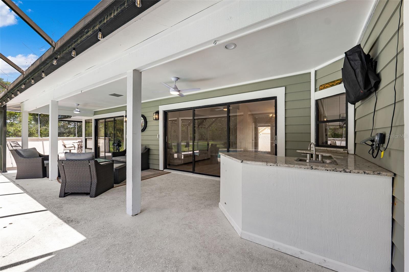 Outdoor kitchen/wet bar and TV in covered pool area