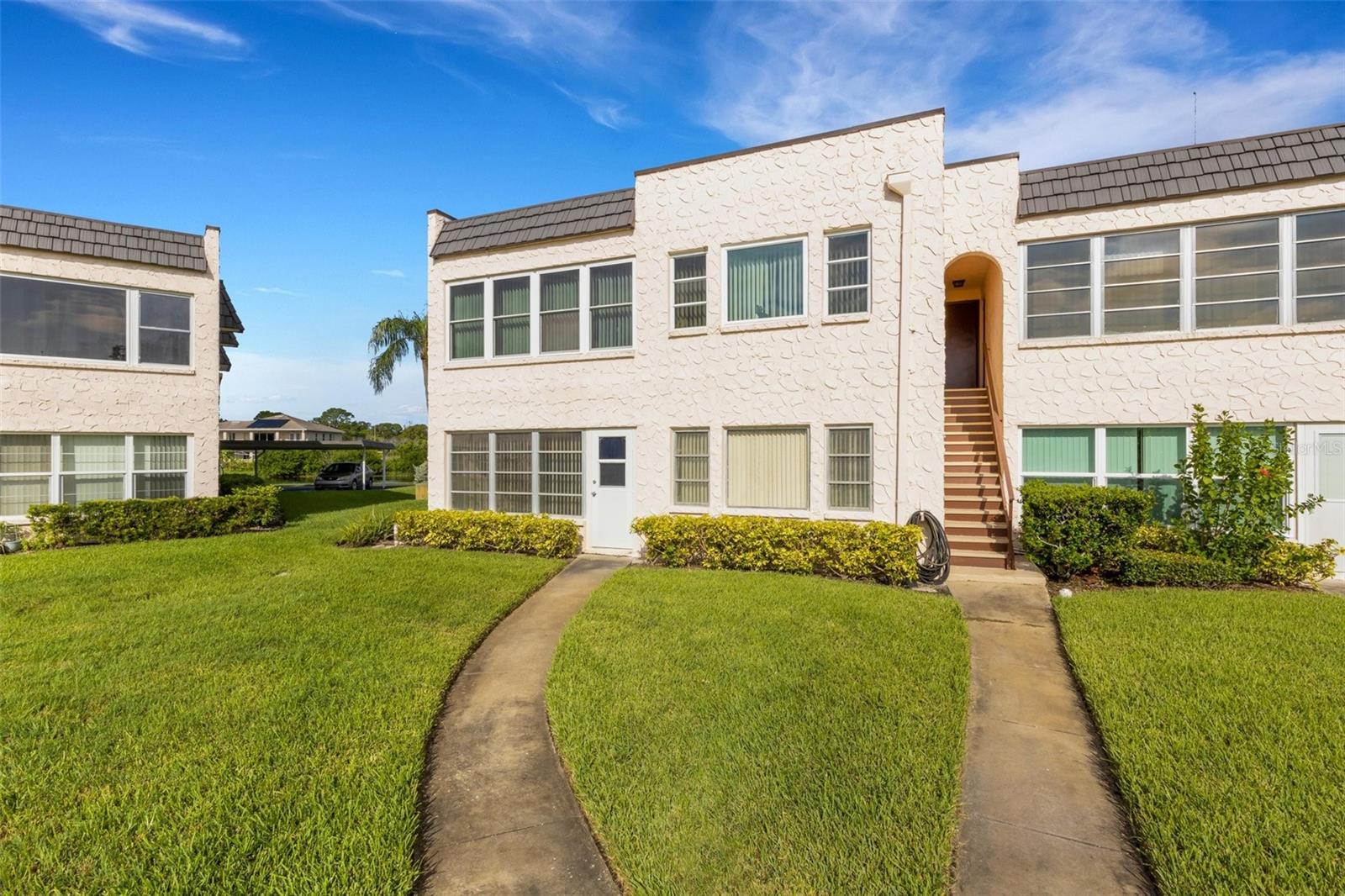 Back of Unit With Pedestrian Door and Sidewalk to Pool and Clubhouse