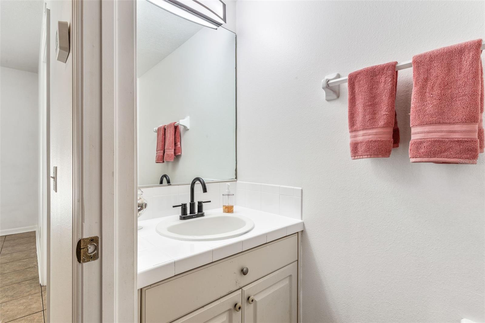 Half bath with new light and faucet fixture, sink and glazed counter.