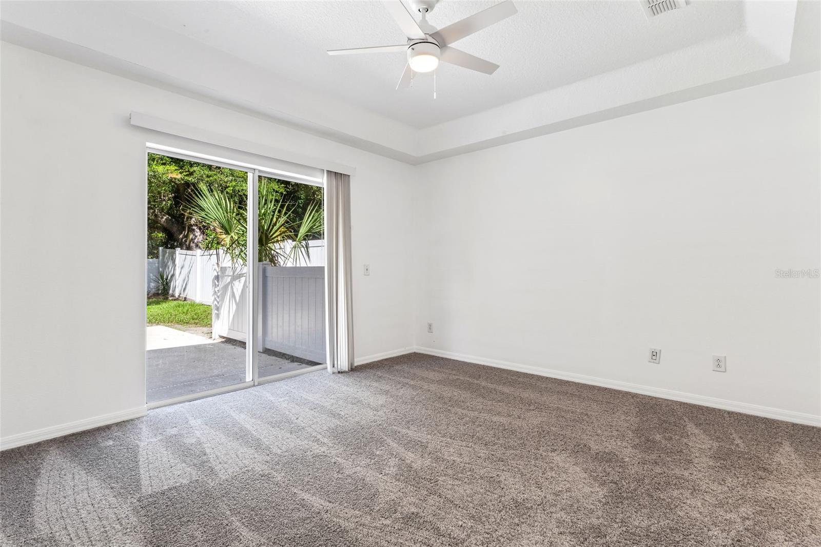 Enter the primary en-suite. New carpet, freshly painted, new light/fan fixture. Sliders to the pool and backyard area.