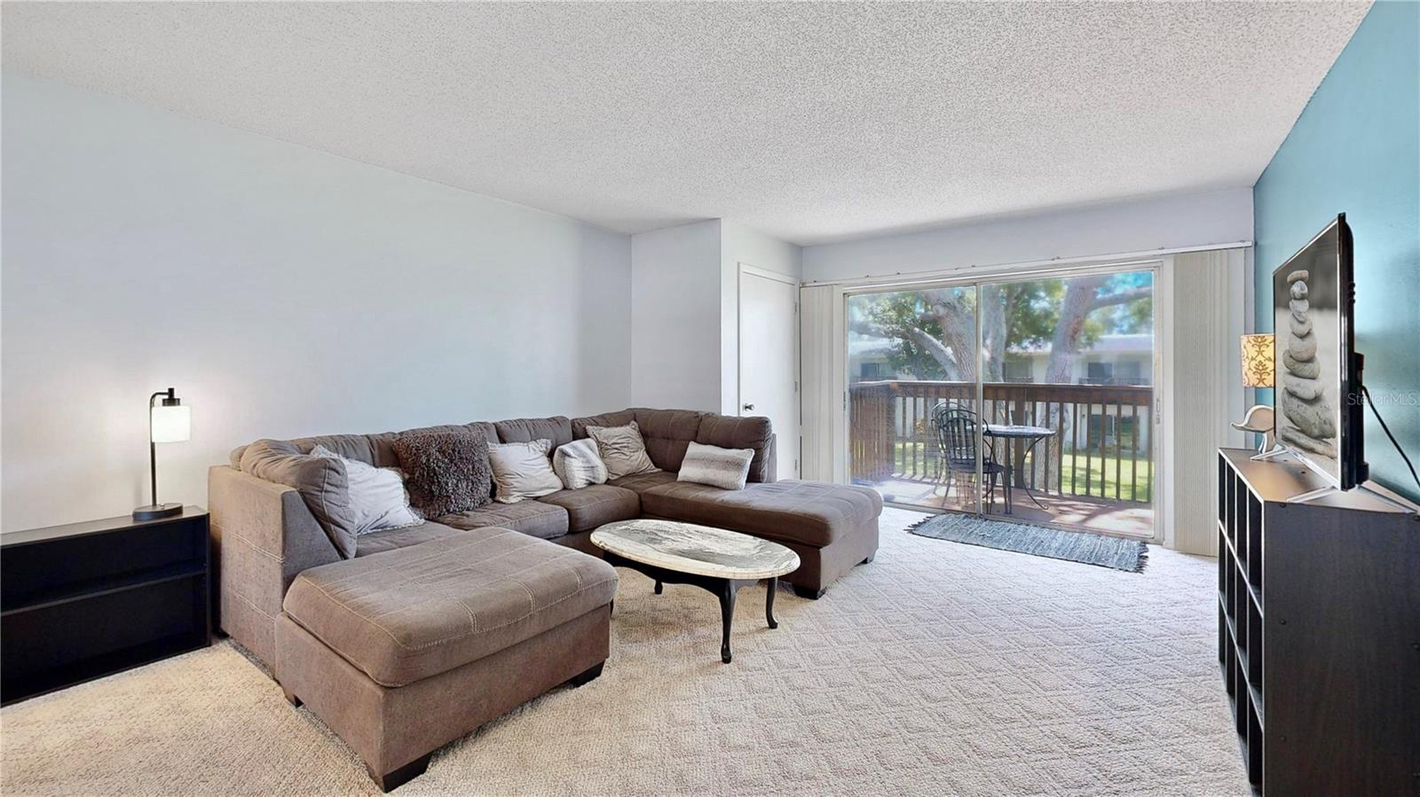 Open living room leads to your beautiful patio overlooking the lush green space with trees.