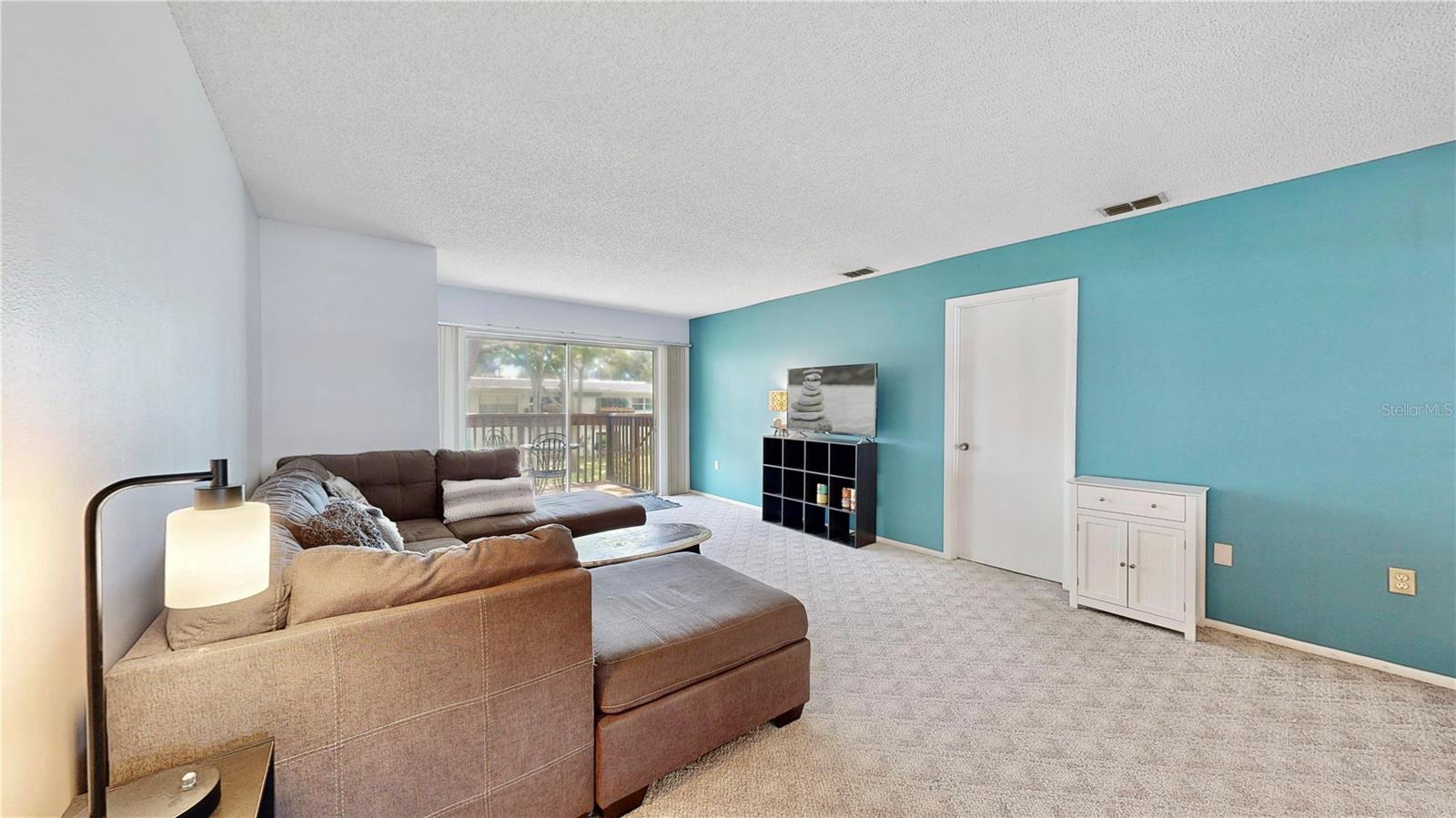 Open living room leads to your beautiful patio overlooking the lush green space with trees.