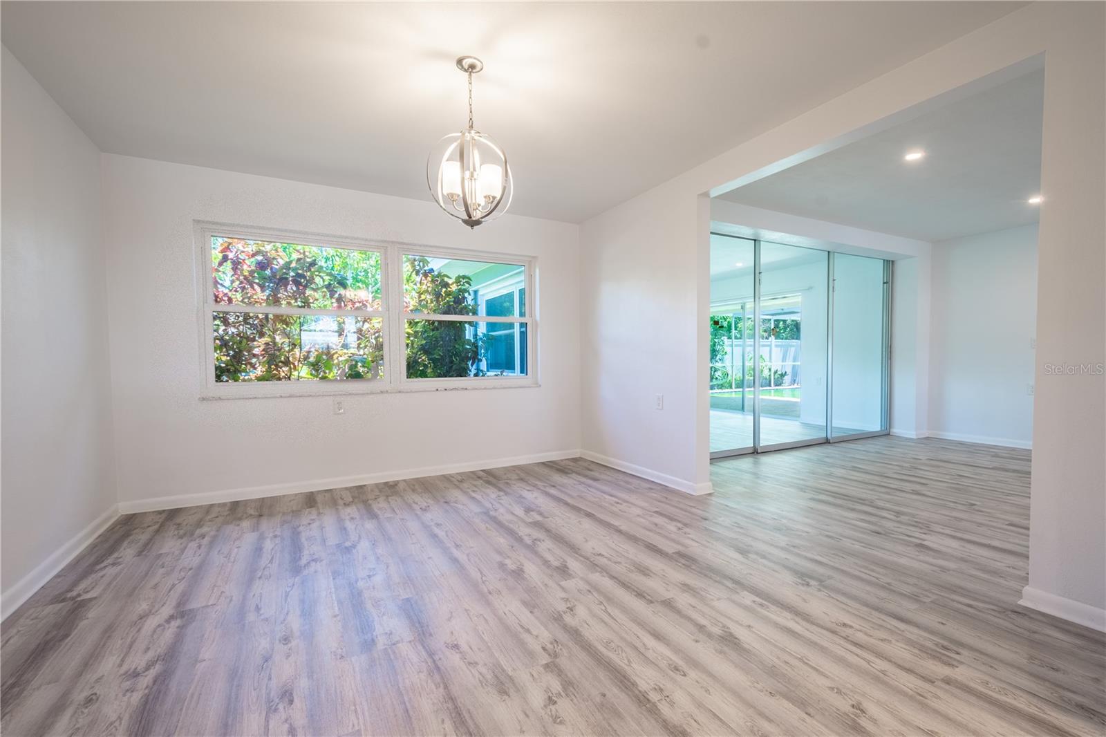 The dining room features luxury vinyl flooring and a picture window that frames the view of the backyard.