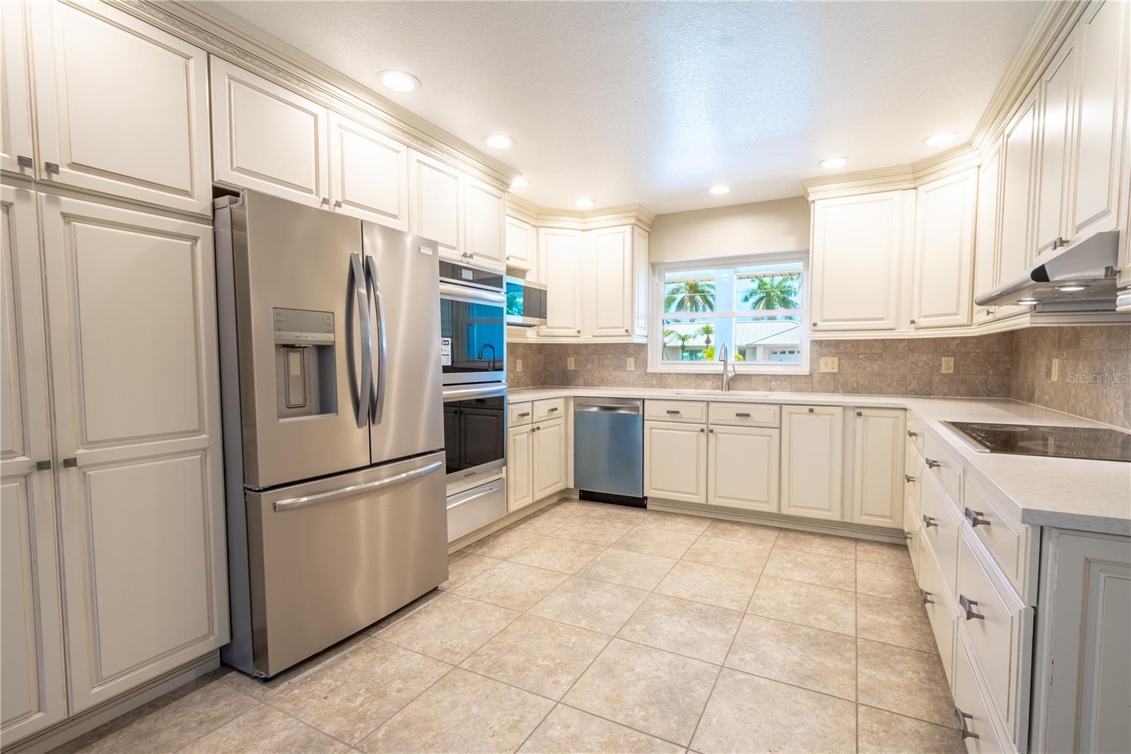 The kitchen features a neutral tone ceramic tile floor and a complimentary tile backsplash.