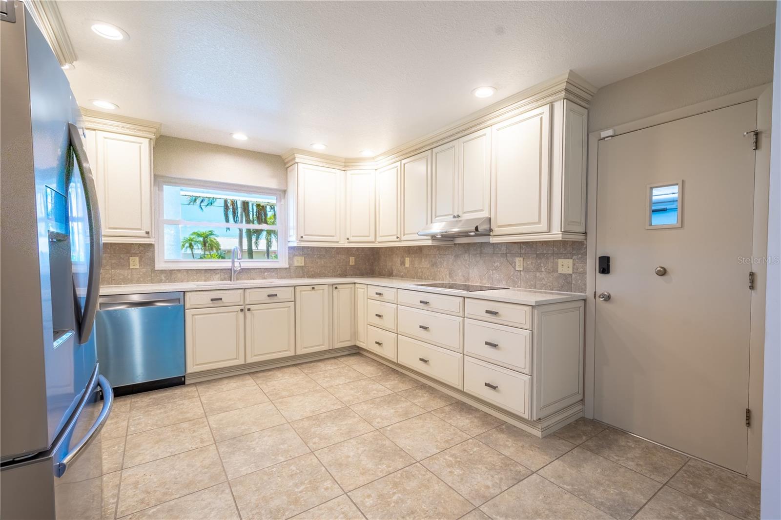 The kitchen features an electric cooktop with a stainless steel exhaust hood.