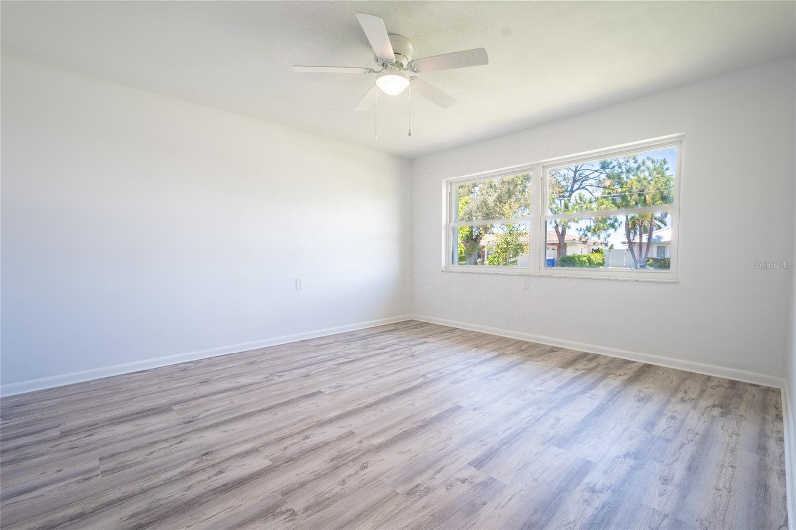 In the third bedroom, you'll find a large picture window, a ceiling fan with integrated lighting, and stylish luxury vinyl flooring.