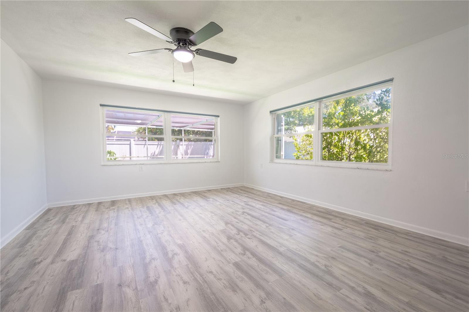 In the primary bedroom, you'll find luxury vinyl flooring, two generous windows for natural light, and a ceiling fan with a built-in light kit.