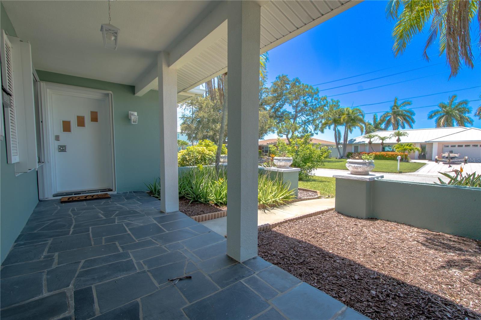 The covered front porch is beautifully illuminated by a pendant light, with the floor elegantly finished in stylish tile.