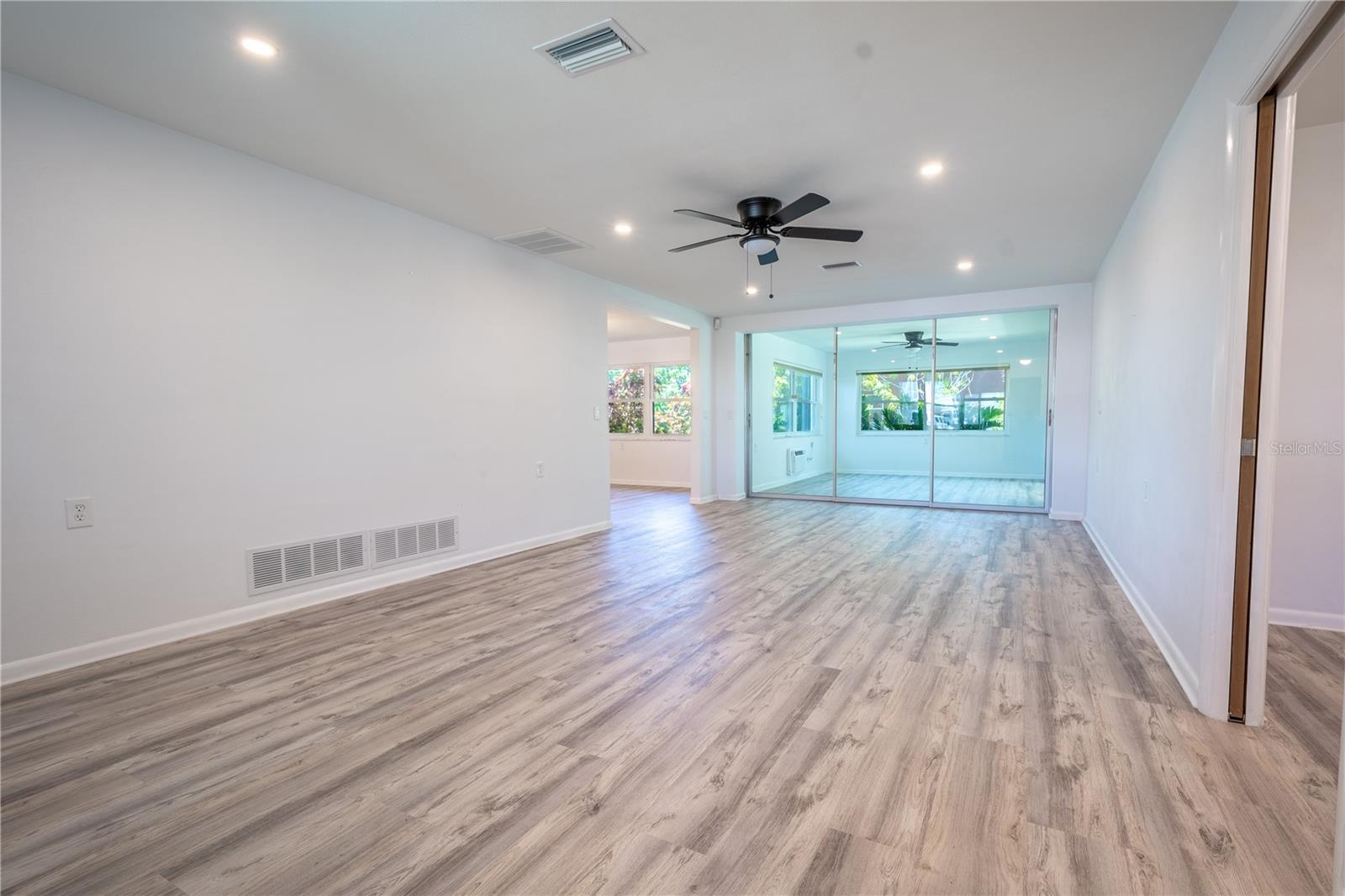 The living room is bathed in neutral tones and features luxury vinyl flooring.