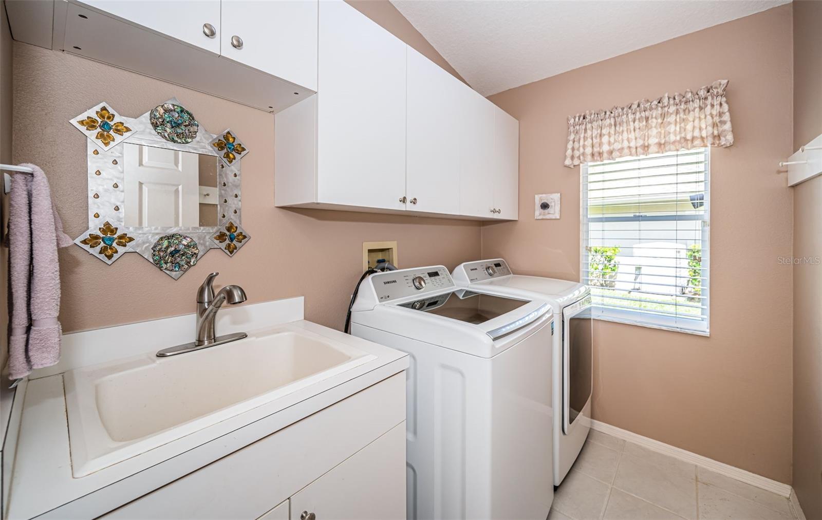 Large laundry room with laundry sink and extra storage, washer and dryer included