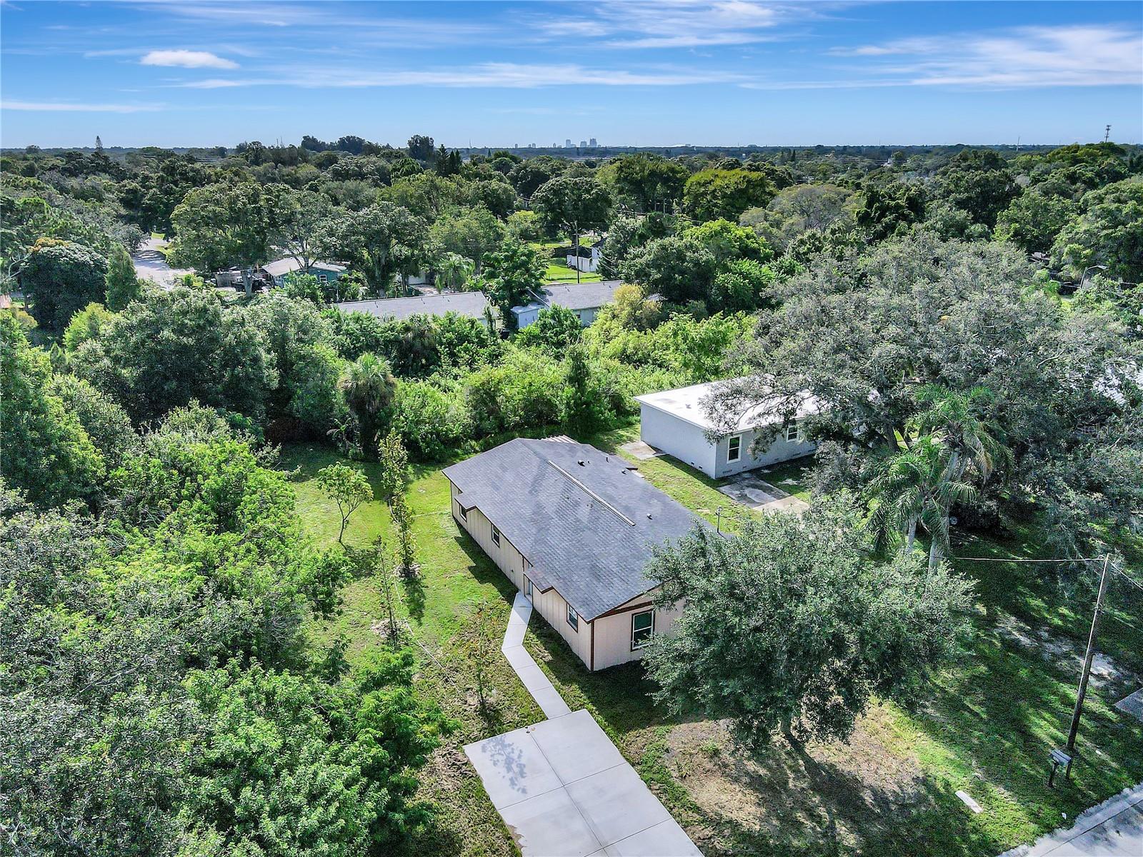 Aerial shot, see light gray house under the shade trees