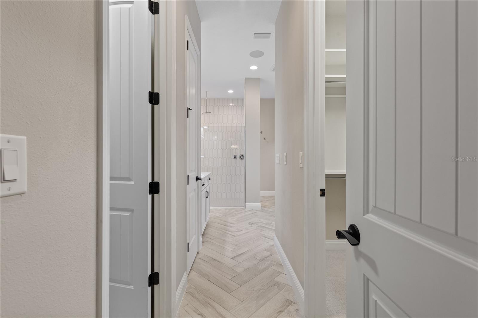 Herringbone tile flooring leads you into the main en suite bathroom with walk in closets