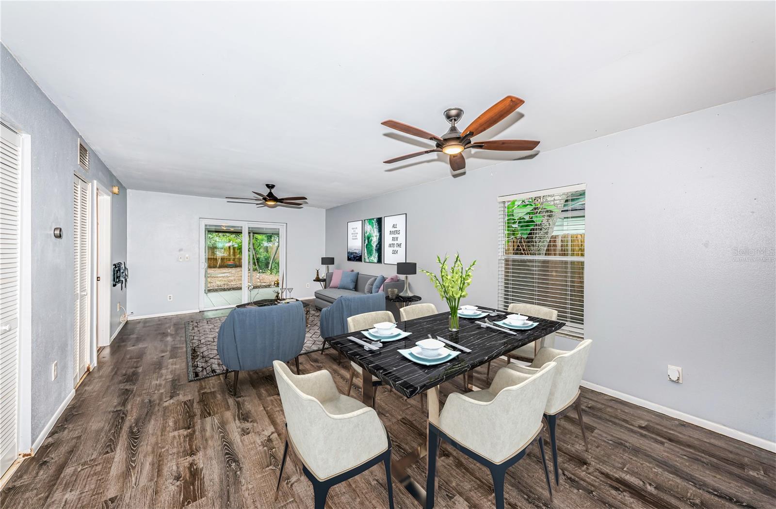 Virtually staged. Dining and living spaces with views into the screened patio and side yard