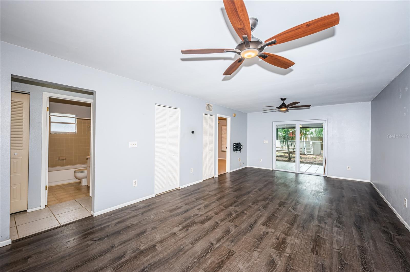 From dining space looking into second bedroom and bathroom with entry to the primary bedroom in the rear of the frame and a view to the screened patio and back yard