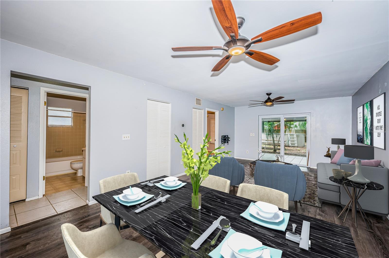 Virtually staged. From dining space looking into second bedroom and bathroom with entry to the primary bedroom in the rear of the frame and a view to the screened patio and back yard