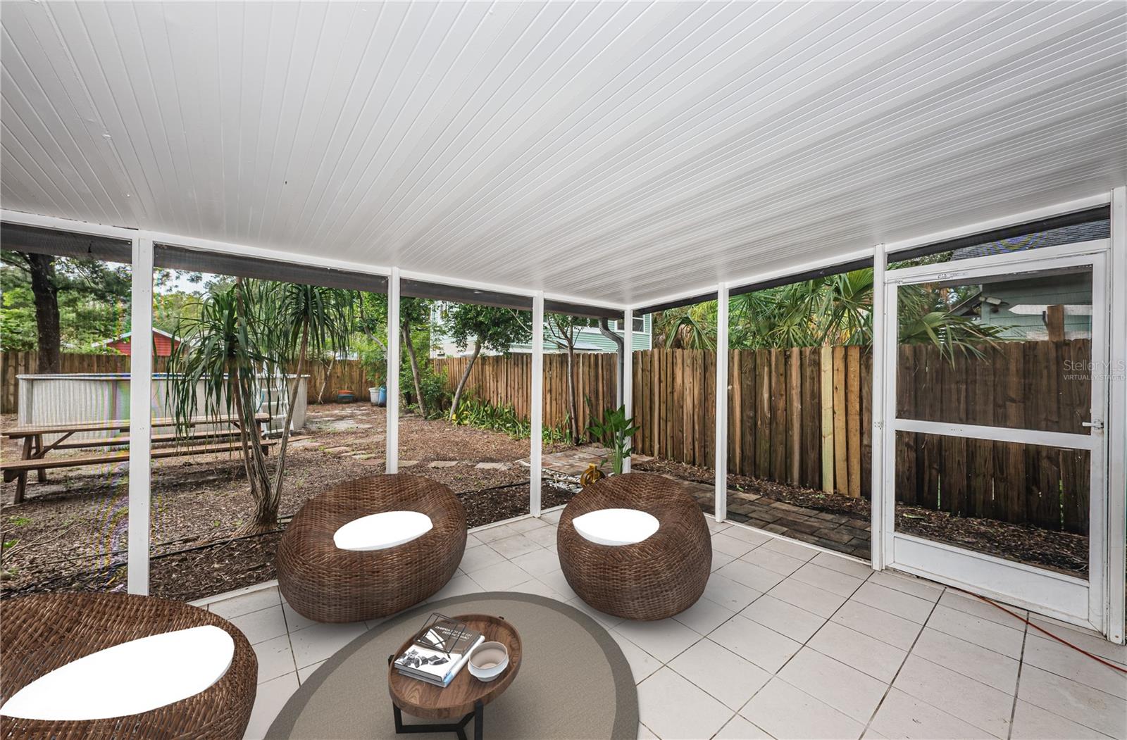 Virtually staged. A view of the screened patio and back yard