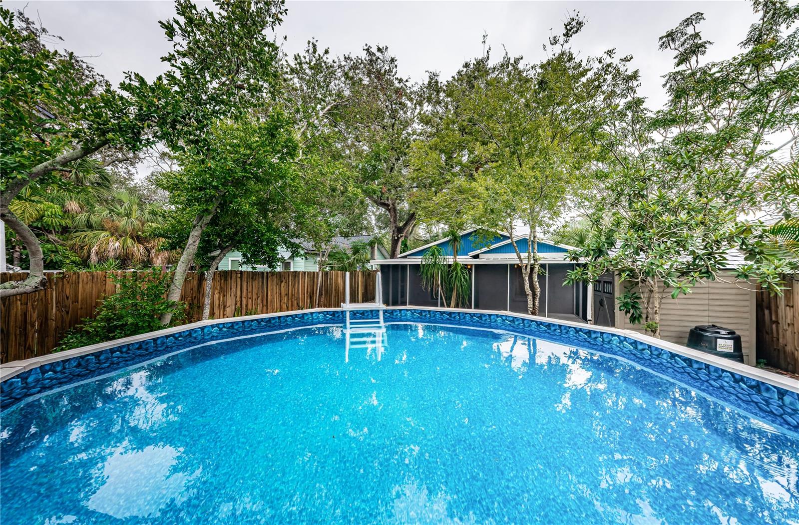 A view of the water in the above-ground pool and back of the house