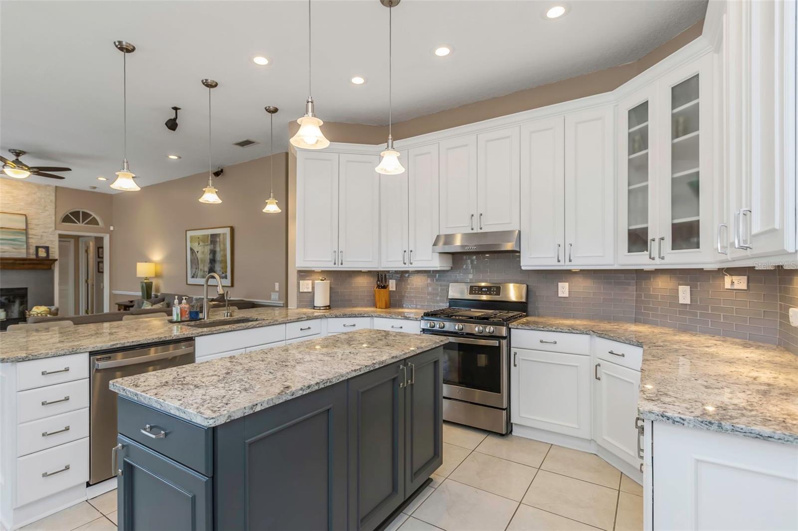 Updated kitchen with stainless appliances, granite counters, glass subway tile backsplash, 42" upper cabinets, and island with storage