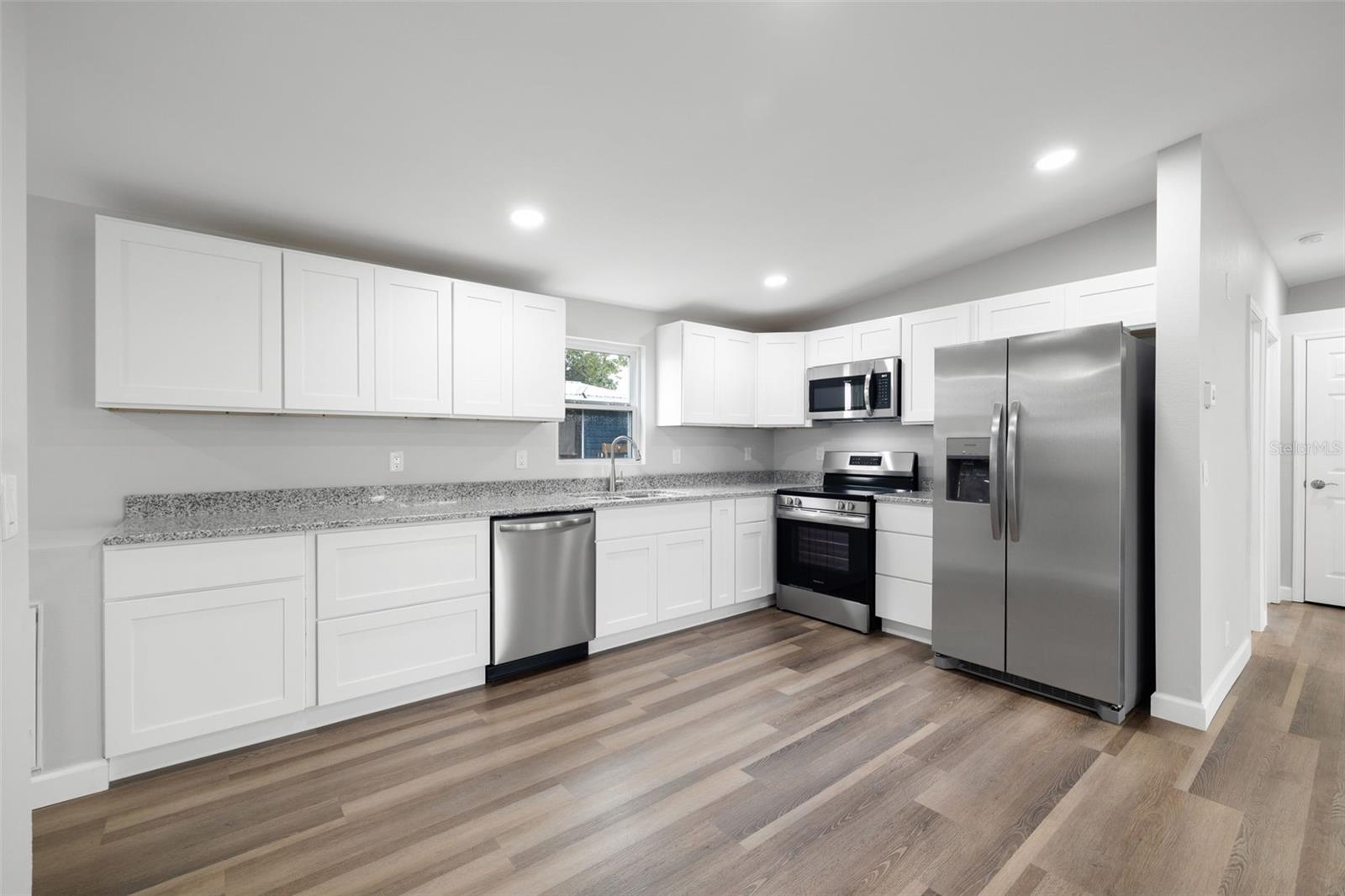 White, shaker-style cabinetry with soft close drawers, brand new stainless steel appliances, recessed lighting, vinyl flooring and new windows!