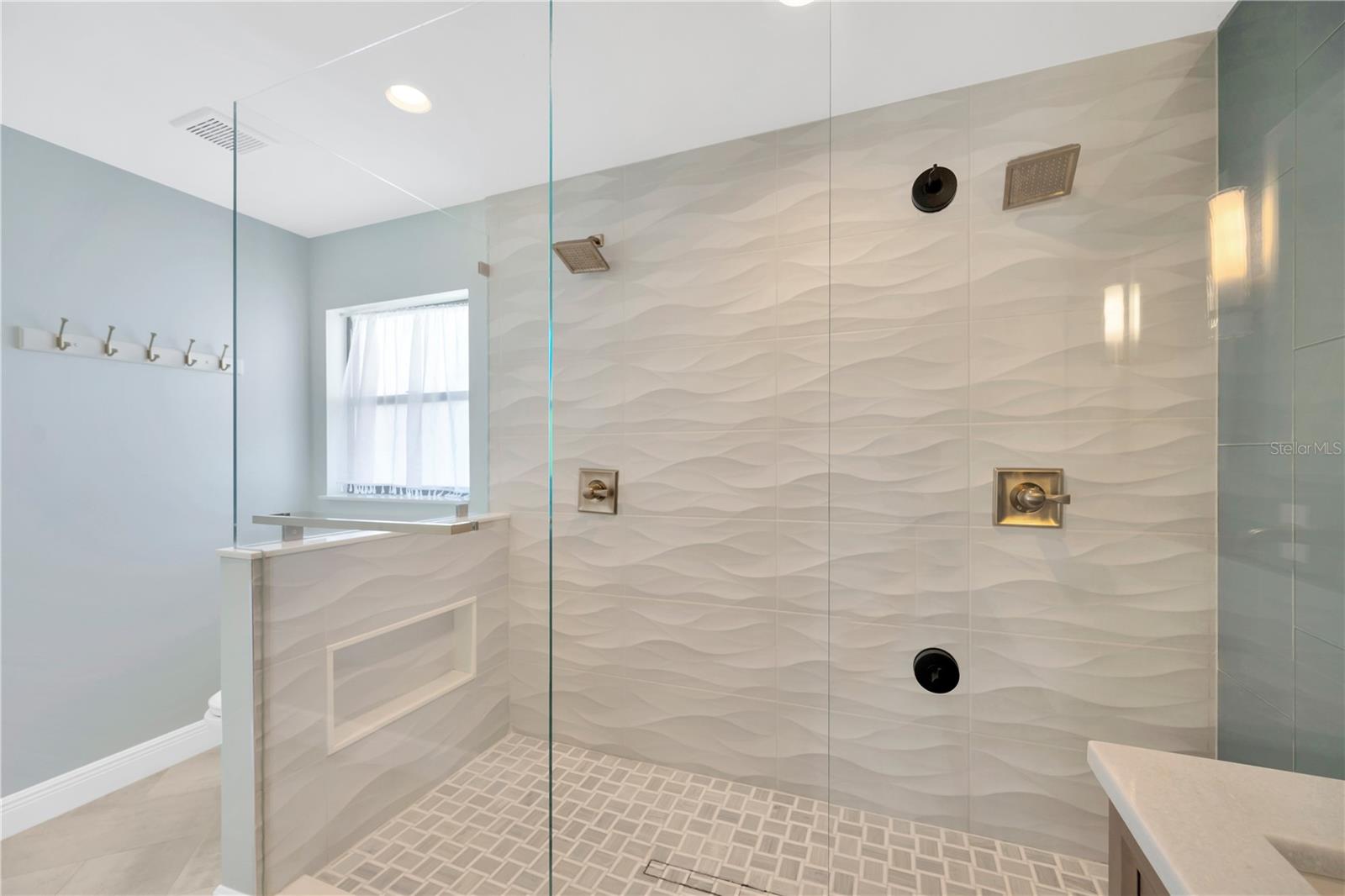 Remodeled step in shower with multiple heads in the primary bathroom.