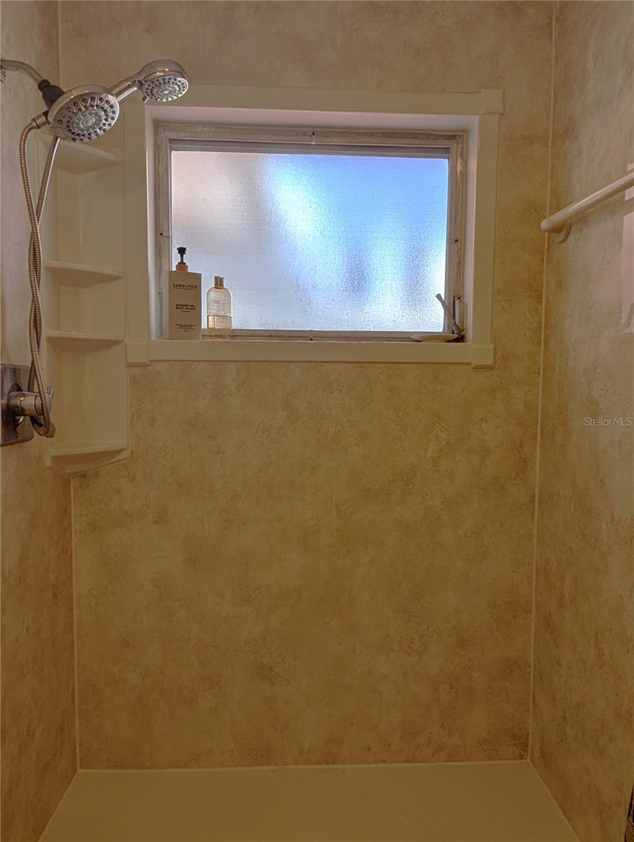 Window is encased with new shower surround.  Shower features built in shelves and new shower heads.