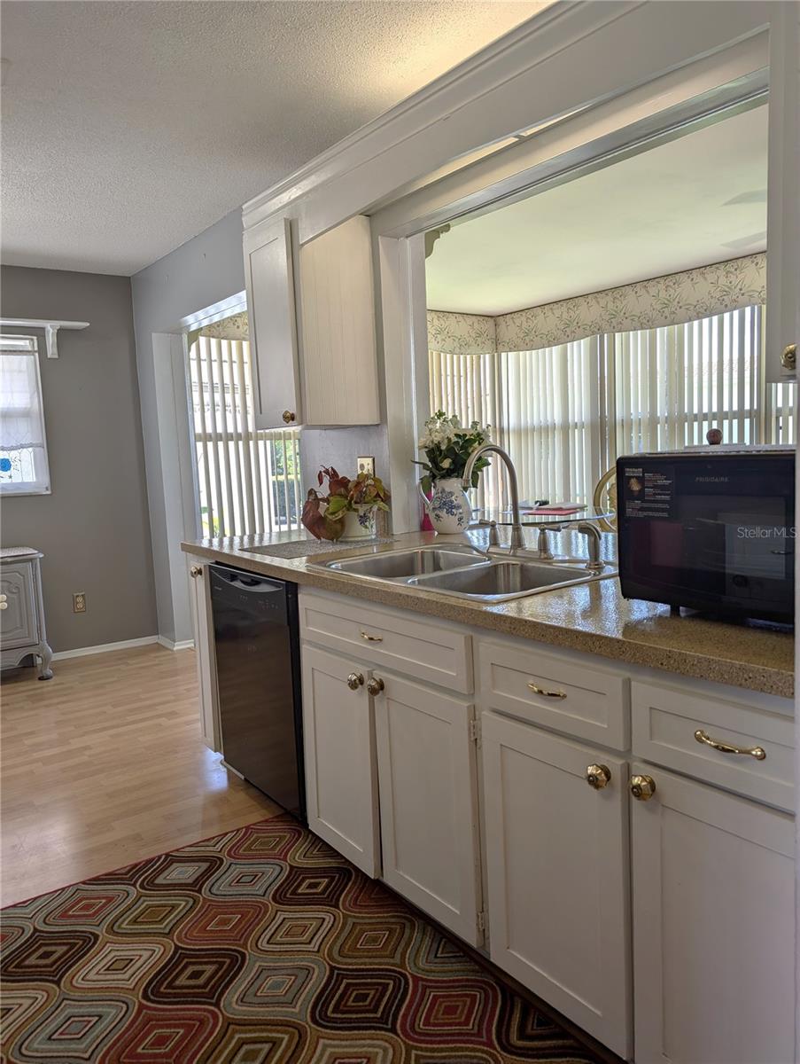 Pass thru window to Florida room.  Kitchen features dishwasher, stainless steel, white cabinetry, resurfaced countertops, laminate wood flooring and a counter top microwave.